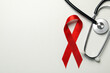 Red awareness ribbon and stethoscope on white background