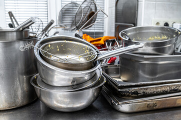 Dirty pots and pans piled up for washing in restaurant kitchen.