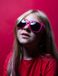 © Stockis - Portrait of a young girl with sunglasses on red background.