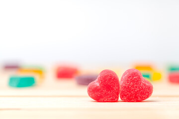 Two  red heart candies coated with sugar  on wooden background