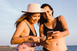 © Mihailo - Girls on beach with cell phone.