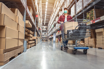 Asian man wearing a shopping mask in Rows of shelves with goods boxes in modern industry warehouse store at factory warehouse storage to decorate the house