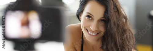 Fotografía Woman lies on the bed in bra and records video on camera