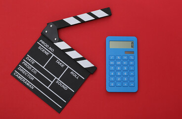 Wall Mural - Film clapper board and calculator on red background. Cinema industry, entertainment. Top view