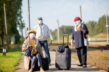 Wall Mural - Positive elderly seniors people with face masks waiting train before traveling during a pandemic