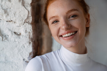 Wall Mural - Redhead happy girl smiling and looking at camera indoors