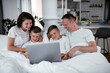 © JustLife - Beautiful parents with kids enjoying at home. Young family watching movie on lap top.