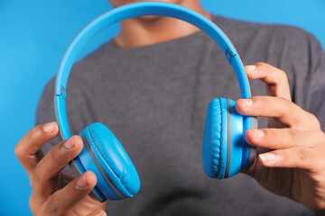 Man hand holding headphone on blue background 