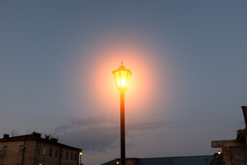 Poster - burning street lamp against the sky. evening city