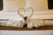 The white towel folded into swan shape and placed like heart shape on bed, luxury room hotel