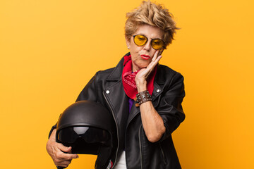 mature old beautiful woman feeling bored, frustrated and sleepy after a tiresome, dull and tedious task, holding face with hand. motorbike concept