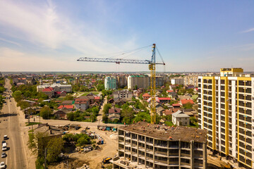 Apartment or office tall building under construction. Working builders and tower cranes on bright blue sky copy space background.