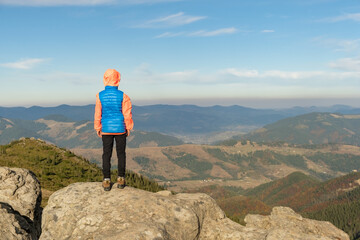 Wall Mural - Young child boy hiker standing in mountains enjoying view of amazing mountain landscape.