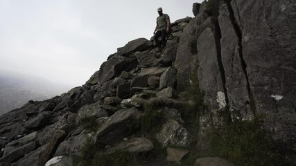 Canvas Print - A man slowly walking down a steep rocky mountain on Tryfan in Snowdonia