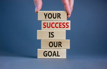 wooden blocks with text 'your success is our goal'. male hand. beautiful grey background, copy space