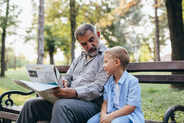 Wall Mural - grandfather and grandson sitting on the bench in park