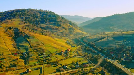 Poster - drone flies to down view on small town with cozy buildings in valley soft sunrise light spring season outdoors