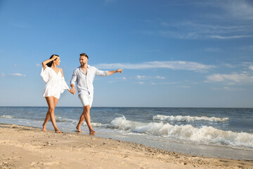 Wall Mural - Happy young couple walking at beach on sunny day