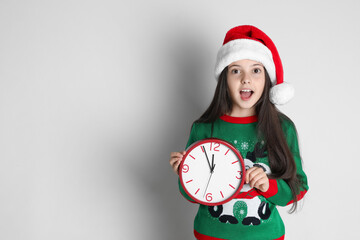 Wall Mural - Girl in Santa hat with clock on white background, space for text. Christmas countdown