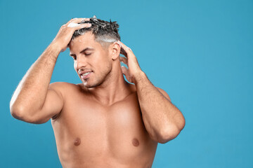 Canvas Print - Handsome man washing hair on light blue background