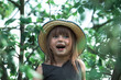 © De Visu - Little cute funny girl in a straw hat in the park.