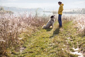 woman and dog in autumn landscape by lake social distancing