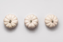 Three White Pumpkin In Middle On Bright Background. Flat Lay In Minimal Style With Copy Space.