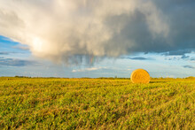 Rural Landscape In Province Of Alberta With Rain Cloud Over Harvested Hay  Field And Hay Bales