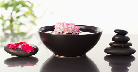 Poster - Pink carnation floating in a bowl with petals on a black stone o