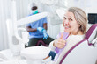 © JackF - Happy cute mature woman sitting in dental chair after teeth cure giving thumb up. High quality photo