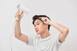 Young asian man holding hair dryer and comb creating new hairdo on white background
