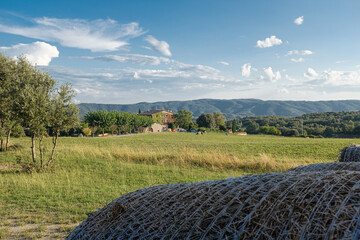 Green rural countryside landscape with farmhouse and straw wheels