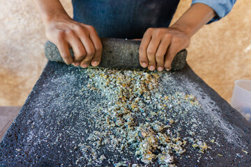 chef grinding corn in stone metate, traditional method to make tortillas, artisan method of grinding corn