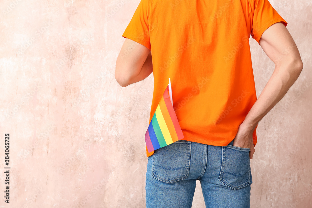 Young man with LGBT flag on color background