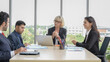 © paepae stocker  - Senior executive female manager leading meeting with team and also using laptop computer at the office workplace background.