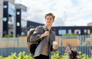 Wall Mural - technology, leisure and people concept - young man or teenage boy with backpack drinking takeaway coffee in city