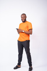 young man holding his phone smiling, standing on a white background, texting concept