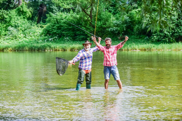 Wall Mural - partners. recreation and leisure outdoor. two happy fisherman with fishing rod and net. hobby and sport activity. Trout bait. father and son fishing. adventures. Big game fishing. male friendship