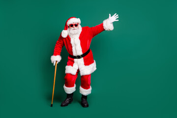 Wall Mural - Full length body size view of his he nice attractive cheery childish playful funky Santa leaning on cane having fun celebration festal day Eve Noel isolated over green color background