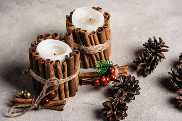 Canvas Print - Decorated scented candles near pine cones on textured and grey background