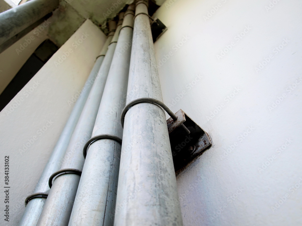 Conduit and clamp on the wall. Large metal electrical wiring pipes are ...