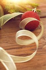 Christmas red ball and Golden ribbon amid the fur tree branch. Wooden background