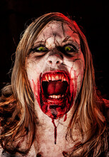 Studio Portrait Of A Female Vampire Of Zombie With Open Mouth, Screaming And Looking At Camera