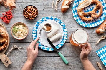 Wall Mural - Celebrating Oktoberfest alone. Traditional food and beer, weisswurst sausage and pretzels.