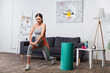 © LIGHTFIELD STUDIOS - brunette and pregnant woman exercising near sport equipment in living room