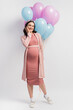 © LIGHTFIELD STUDIOS - joyful and pregnant woman in dress near balloons on white