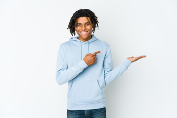 Young african american rasta man excited holding a copy space on palm.