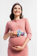 © LIGHTFIELD STUDIOS - joyful pregnant woman with floral belt standing isolated on white