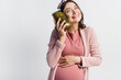 © LIGHTFIELD STUDIOS - pleased and pregnant woman holding jar with pickled cucumbers isolated on white