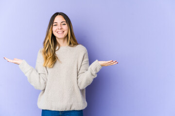 Young caucasian woman isolated on purple background makes scale with arms, feels happy and confident.